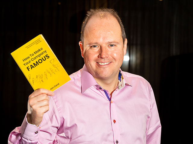 Jon Card holding his book